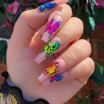 Hand of a person painted in a light pink color and adorned with vibrant and colorful butterflies