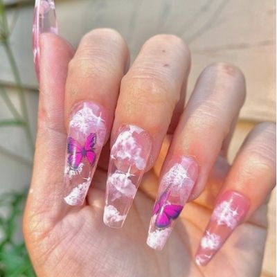 a person's hand with long nails painted in pink and decorated with butterflies