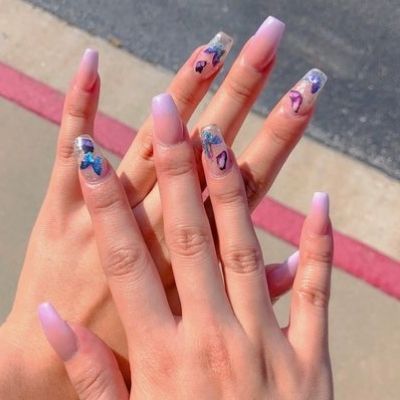 The person's hand showcases pink-painted nails adorned with elegant blue butterflies