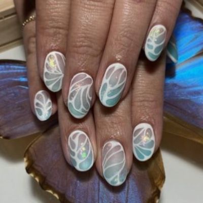 Hand of a person with nails painted in a design resembling printed butterfly wings